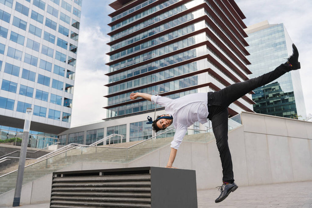 Happy and handsome adult businessman wearing elegant suit doing acrobatic trick moves in the city, alternative concept for business advertisement with energetic and creative people - Фото, зображення