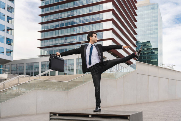 Happy and handsome adult businessman wearing elegant suit doing acrobatic trick moves in the city, alternative concept for business advertisement with energetic and creative people - Fotoğraf, Görsel