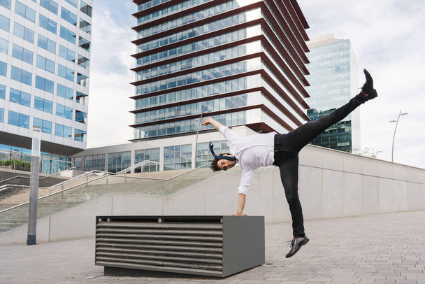 Happy and handsome adult businessman wearing elegant suit doing acrobatic trick moves in the city, alternative concept for business advertisement with energetic and creative people - Zdjęcie, obraz