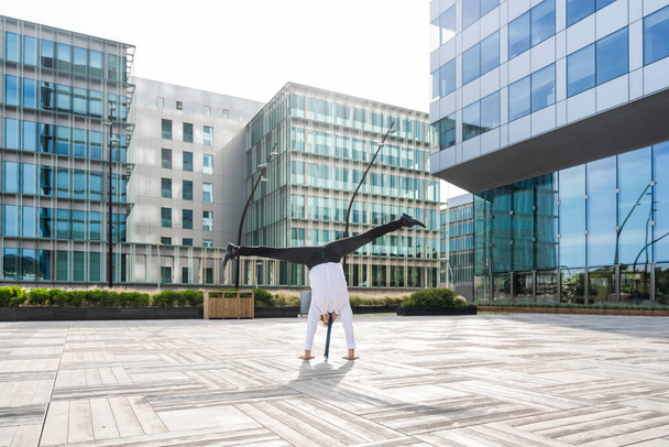 Happy and handsome adult businessman wearing elegant suit doing acrobatic trick moves in the city, alternative concept for business advertisement with energetic and creative people - Foto, afbeelding