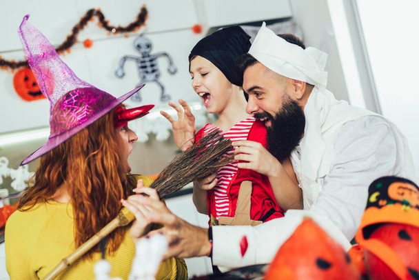 Happy family mother, father and son in costumes on a celebration of Halloween - 写真・画像
