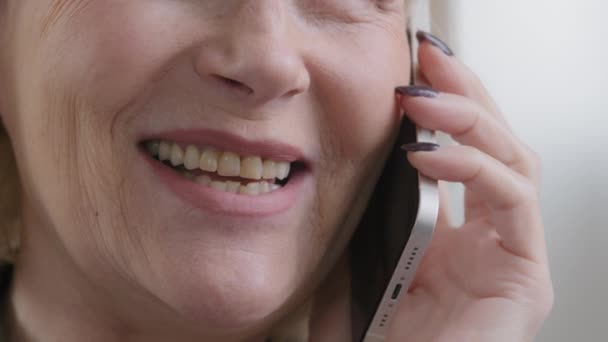 Close up half wrinkled face female mouth smiling Caucasian old senior woman talking mobile phone conversation speaking smile chatting with friend family answer call unrecognizable elderly lady talk - Materiaali, video