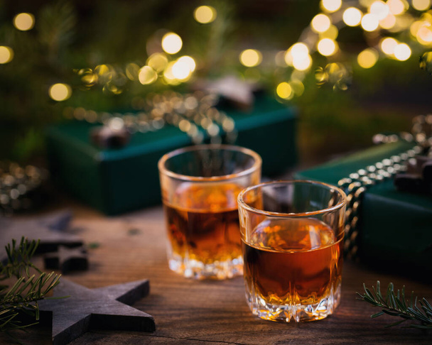 Two glasses of whiskey or bourbon with Christmas decoration on dark background. New Year, Christmas and winter holidays whiskey mood concept - Valokuva, kuva