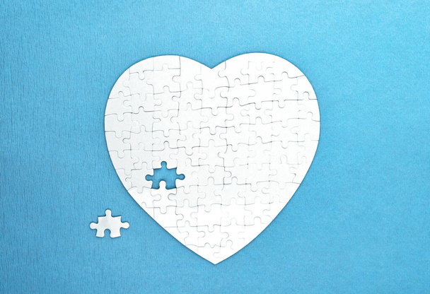 White puzzles shape of heart on blue background. Health care concept - Fotó, kép