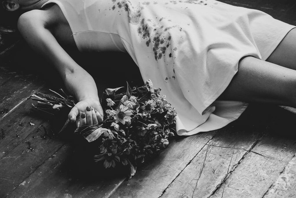 A girl in a bloody white dress lies on the floor of the house and next to a bouquet of flowers, the war in Ukraine, a girl killed by a Russian soldier, violence against Ukrainian women by Russians - Photo, image