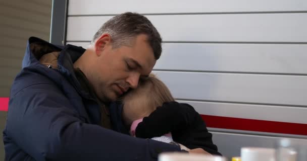Pečující a unavený otec drží spící dcerku ve zbrani, zatímco čekají na let na letišti - Záběry, video