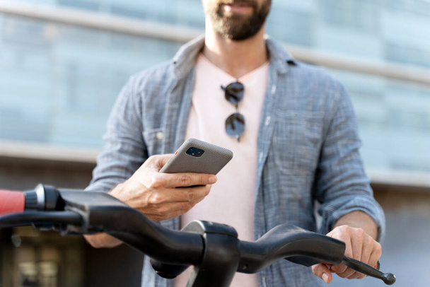 Чоловік турист використовує мобільний додаток, сканує QR-код для оренди електричного скутера на вулиці, вибірковий фокус. концепція екологічного транспорту
 - Фото, зображення