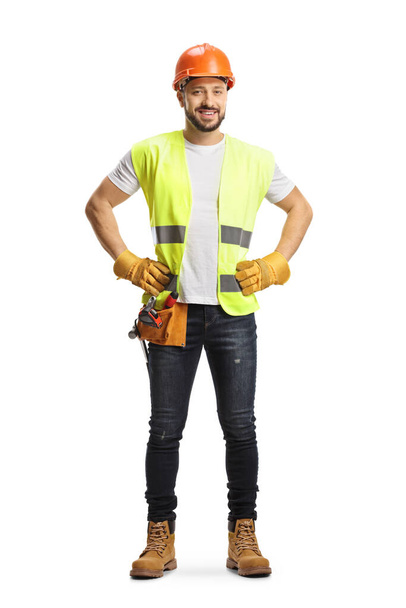 Full length portrait of a site engineer wearing a tool belt and smiling at camera isolated on white background - Foto, afbeelding