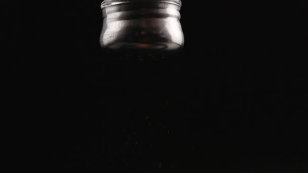 black pepper falling out from pepper-pot on black background in slow motion - Séquence, vidéo