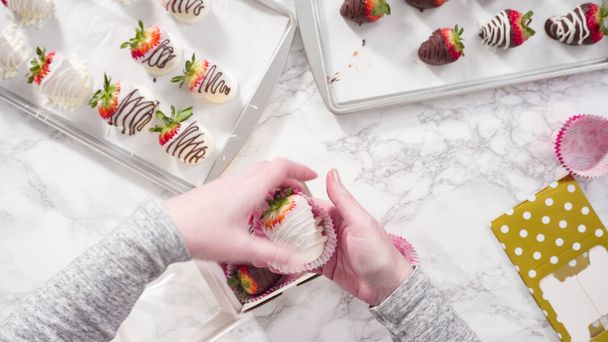 Flat lay. Step by step. Packaging chocolate dipped strawberries into a paper box for a gift. - Photo, Image