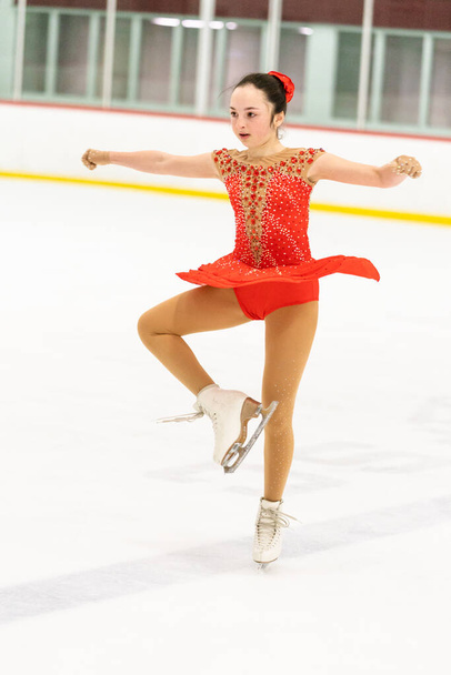 Teenage girl practicing figure skating on an indoor ice skating rink. - Фото, изображение