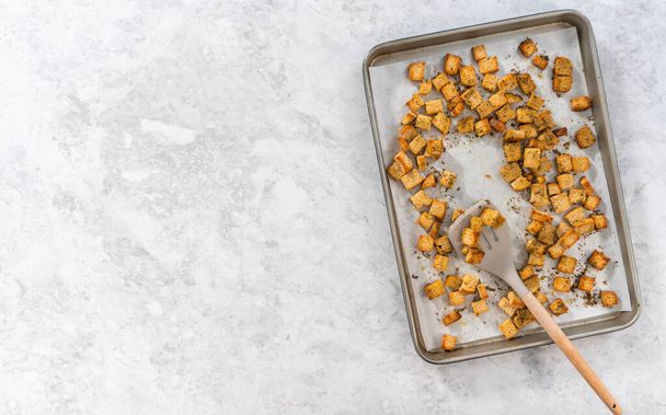 Flat lay. Cooling freshly dried croutons on a baking sheet lined with parchment paper. - Photo, image