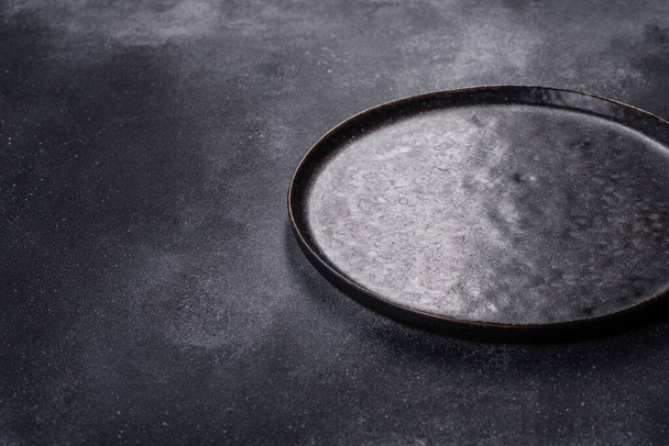 Empty black plates, fork and knife on a gray background. Top view, copy space - Photo, Image