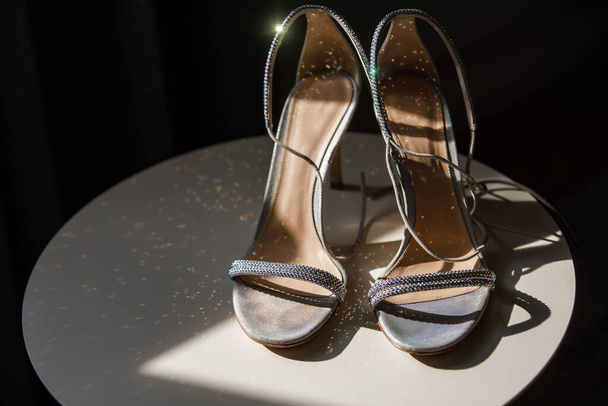 Серебряная свадебная обувь стоит на столе. - Фото, изображение