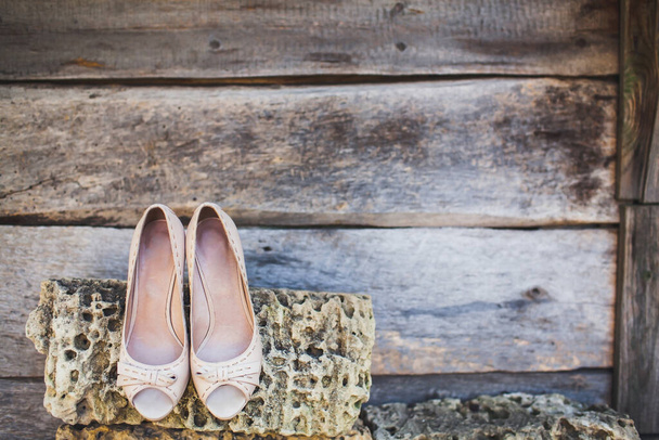 Beige bruiloft schoenen opknoping op een steen. - Foto, afbeelding