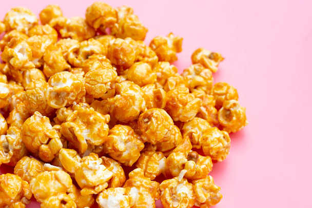 Honey caramel popcorn on pink background. - Photo, image