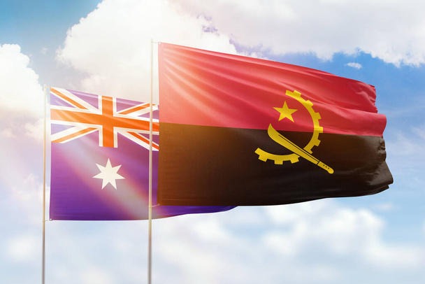 Sunny blue sky and flags of angola and australia - Foto, afbeelding