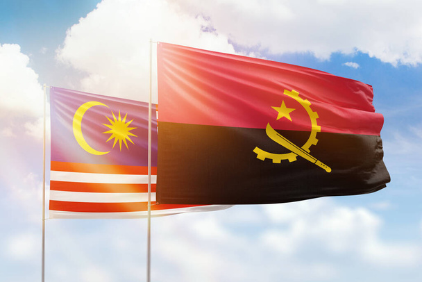 Sunny blue sky and flags of angola and malaysia - 写真・画像