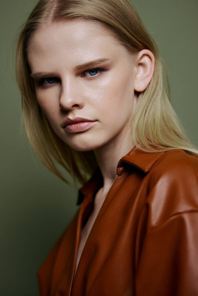 Headshot portret van stijlvolle zelfverzekerde professionele blonde model kijkt naar de camera. Close-up shot in studio op over olijfgroene achtergrond. Hoge kwaliteit foto - Foto, afbeelding