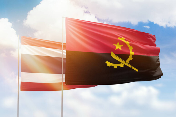 Sunny blue sky and flags of angola and thailand - Photo, Image