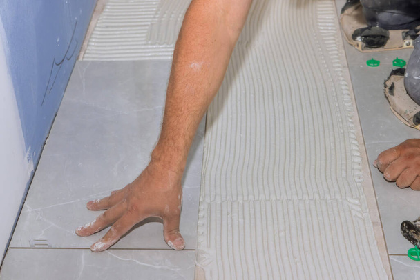 Покращення будинку будівельник плитка кладе керамічну плитку підлогу на клей
 - Фото, зображення