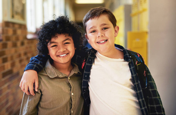 Friends are the best part of school. two young boys standing in the hallway at school with their arms around each other - Foto, imagen