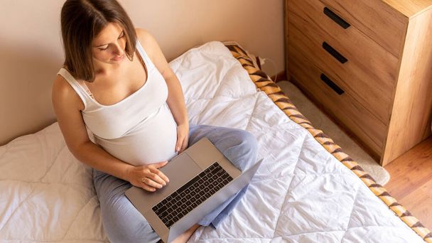 Hamilelik bilgisayarı. Elinde dijital bilgisayar tutan hamile bir kadın. Taşınabilir hamilelik çevrimiçi annelik not defteri uygulaması. Hamilelik kavramı, annelik, bebek doğumu beklentisi - Fotoğraf, Görsel
