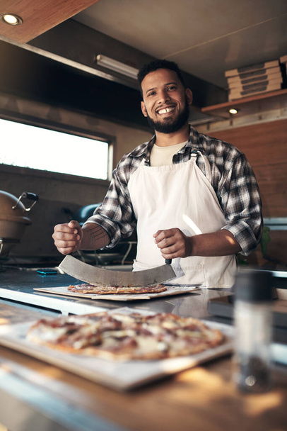 Pizzanız neredeyse hazır. Yakışıklı bir genç adam restoranında taze yapılmış bir pizzayı hazırlıyor. - Fotoğraf, Görsel