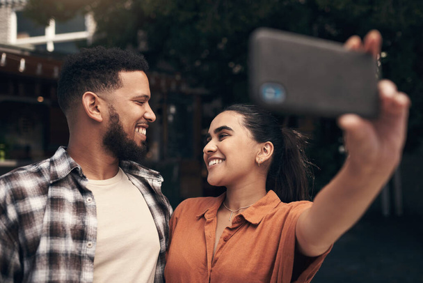 We have to capture the perfect day out. two young friends standing outside a restaurant and using a cellphone to take a selfie - Фото, изображение