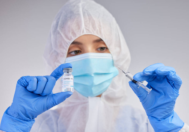 Together we can save humanity. a young female nurse holding a needle and vial of vaccination fluid against a studio background - Фото, изображение