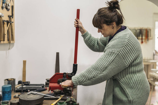 Stock photo of adult woman using tools in jewelry workshop. - Zdjęcie, obraz