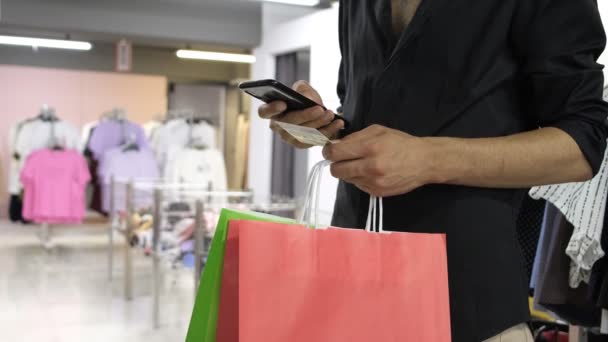 Шоппинг по телефону, шоппинг по телефону с сумкой в руке, онлайн шоппинг рекламные изображения в магазине одежды - Кадры, видео