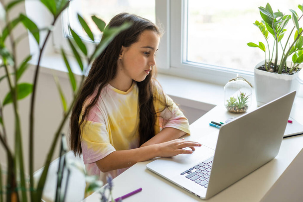 Opgewonden tiener meisje zitten in woonkamer met laptop, tijdens Webinar thuis. Online School Tests Concept. - Foto, afbeelding