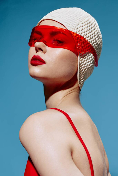 Egy magabiztos, elegáns fiatal nő fehér úszósapkában és piros szemüvegben arrogánsan néz a kamerába. Fejlövés a stúdióban. Kiváló minőségű fénykép - Fotó, kép