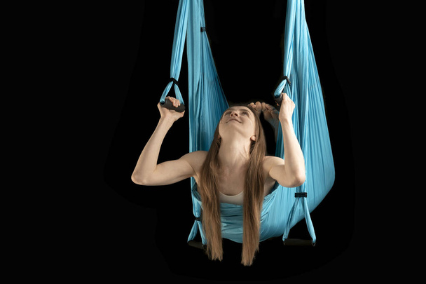 Young woman is engaged in aerial gymnastics. Girl trains with sports hammock. Fly yoga - Φωτογραφία, εικόνα
