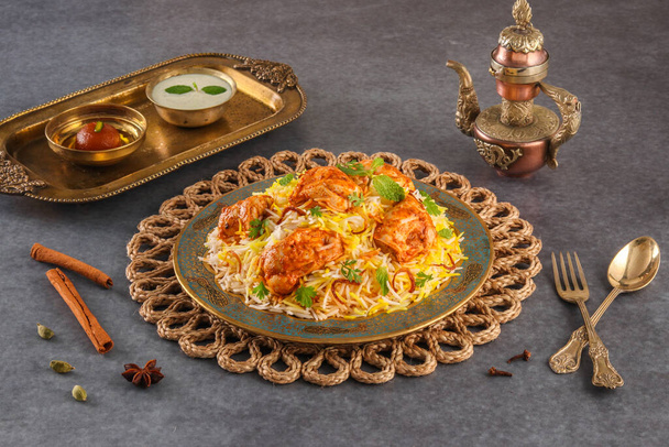 Hint baharatlı yemek tereyağlı tavuk biryani veya Murgh Makhani Biryani raita ve gulab jamun ile gri arkaplanda bir tabak kenar manzaralı ramdan yemeği servis edilir. - Fotoğraf, Görsel