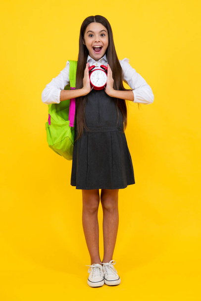 School girl and education concept. Back to school. Schoolchild, teenage student girl with clock alarm, time to study. Excited face, cheerful emotions of teenager girl - Фото, изображение