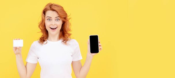 surprised girl showing credit or debit card and smartphone to make online shopping, shopping online. Woman isolated face portrait, banner with mock up copy space - Φωτογραφία, εικόνα