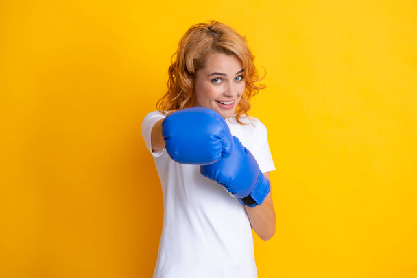 Redhead woman with boxing gloves punching isolated on yellow background. - 写真・画像