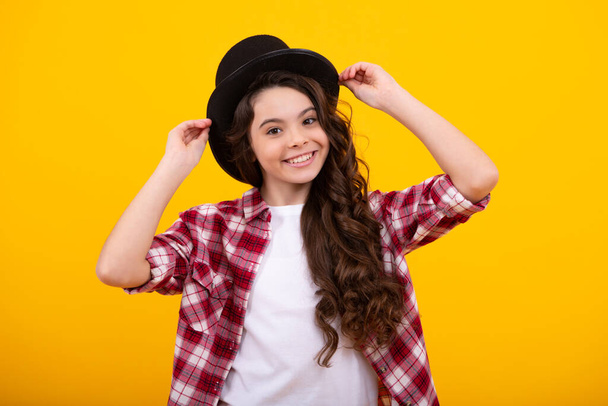 Child teen girl in magician hat, cylinder hat isolated on yellow background. Headwear. Clothes accessories. Fashion headwear for gentlemen in vintage style, old classic cylinder - Zdjęcie, obraz