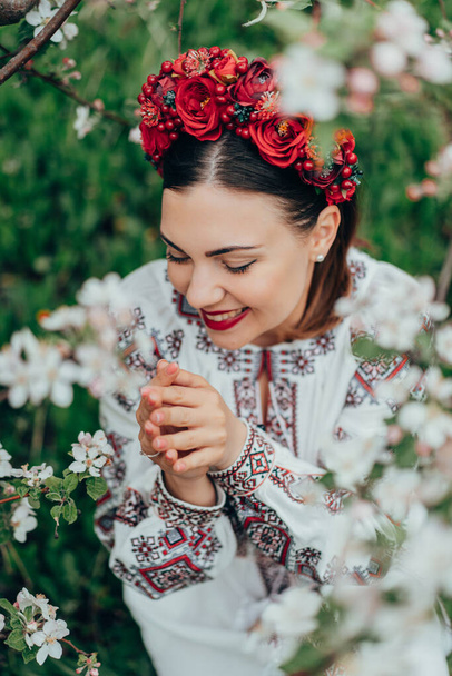 Attractive ukrainian woman in traditional embroidery vyshyvanka dress and red flowers wreath. Ukraine, freedom, culture, national costume, victory in war. High quality photo - Foto, Imagen