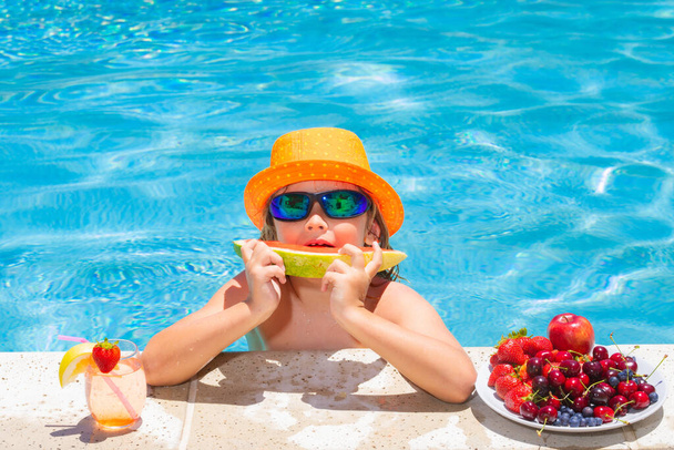 Happy child playing in swimming pool. Summer kids vacation. Summer fruit for children. Little kid boy relaxing in a pool having fun during summer vacation - Photo, Image
