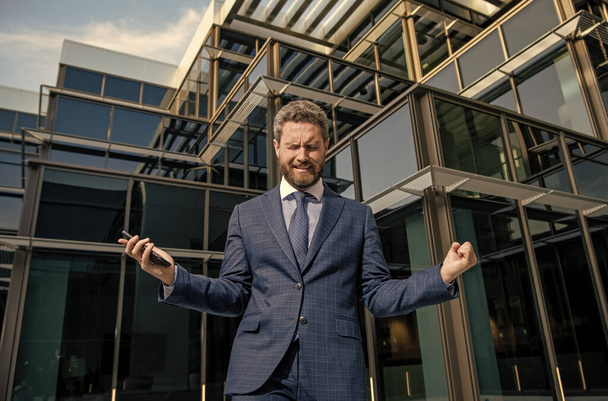 crying bearded businessman in formal suit with smartphone, bankruptcy. - Photo, Image