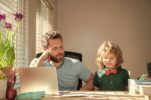 back to school. concentrated father and son use computer at home. family and parenthood blog. boy do homework with private teacher. webinar video lesson. online education on laptop. homeschooling. - Photo, Image