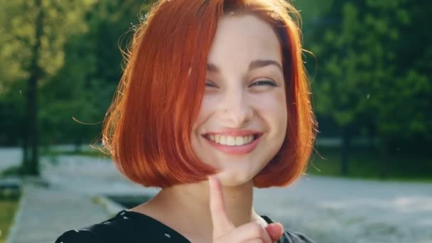 Excited caucasian creative young student girl redhead woman makes gesture raises finger come up with new good idea cunning plan feel motivation inspiration stands outdoors ponder fantasy imagination - Filmmaterial, Video