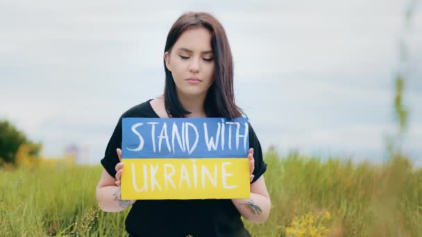 Depressieve overstuur meisje vrouw verhoogt kunstwerk banner karton met politieke inscriptie stand met Oekraïne demonstreren demonstreren kleurrijke geel blauw patriottische bordje vraagt hulp voor Oekraïense natie - Video