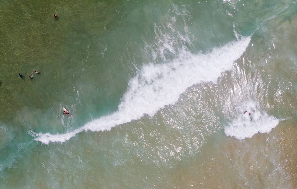 An aerial top view of people surfing and swimming in a sea on a sunny day - Foto, Imagem