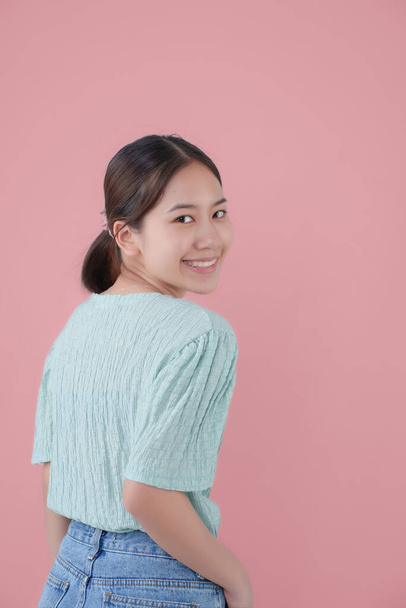 jong aziatisch mooi meisje over geïsoleerd roze achtergrond wijzend vinger naar de zijkant met kopieerruimte. - Foto, afbeelding