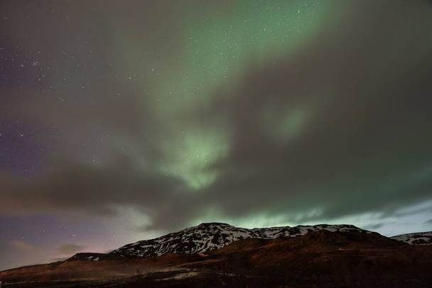 Un paysage avec des montagnes et des lumières polaires en arrière-plan en Islande - Photo, image