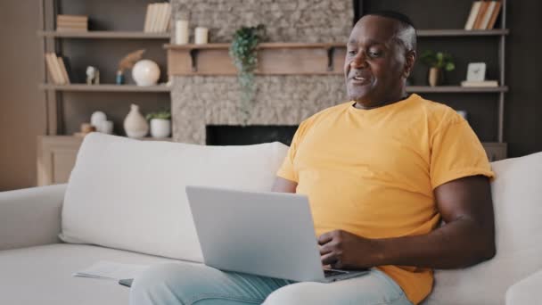 Afro-Amerikaanse man senior vijftiger jaren man werken laptop thuis praten online met mooie lieverd toont liefde gebaar met handen plooien vingers in hart vorm tekenen romantische liefdevolle symbool flirten - Video